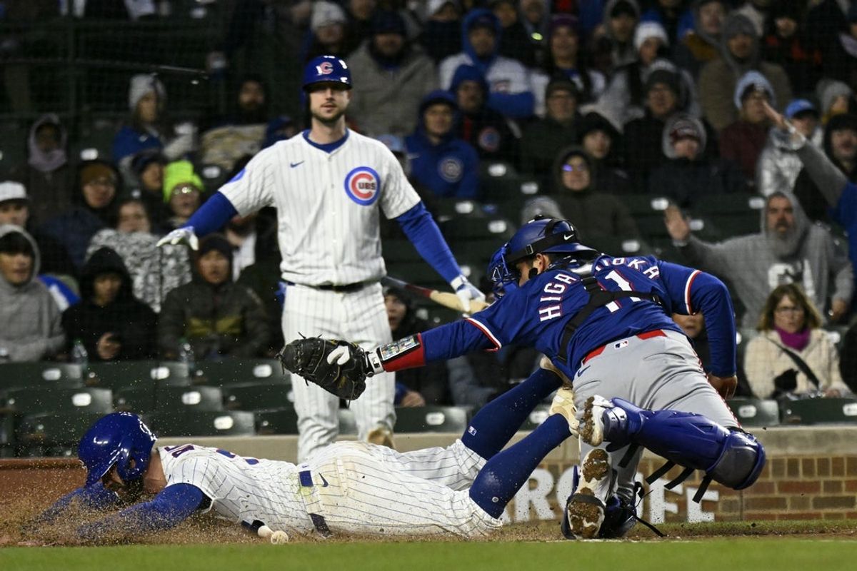 Apr 7, 2025; Chicago, Illinois, USA;  Chicago Cubs third base Jon Berti (5) scorers past Texas Rangers catcher Kyle Higashioka (11) during the third inning at Wrigley Field. Mandatory Credit: Matt Marton-Imagn Images