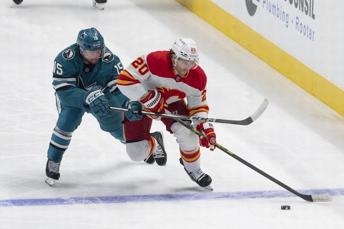 Apr 7, 2025; San Jose, California, USA;  San Jose Sharks right wing Nikolai Kovalenko (15) and Calgary Flames left wing Blake Coleman (20) fight for control of the puck during the first period at SAP Center at San Jose. Mandatory Credit: Stan Szeto-Imagn Images