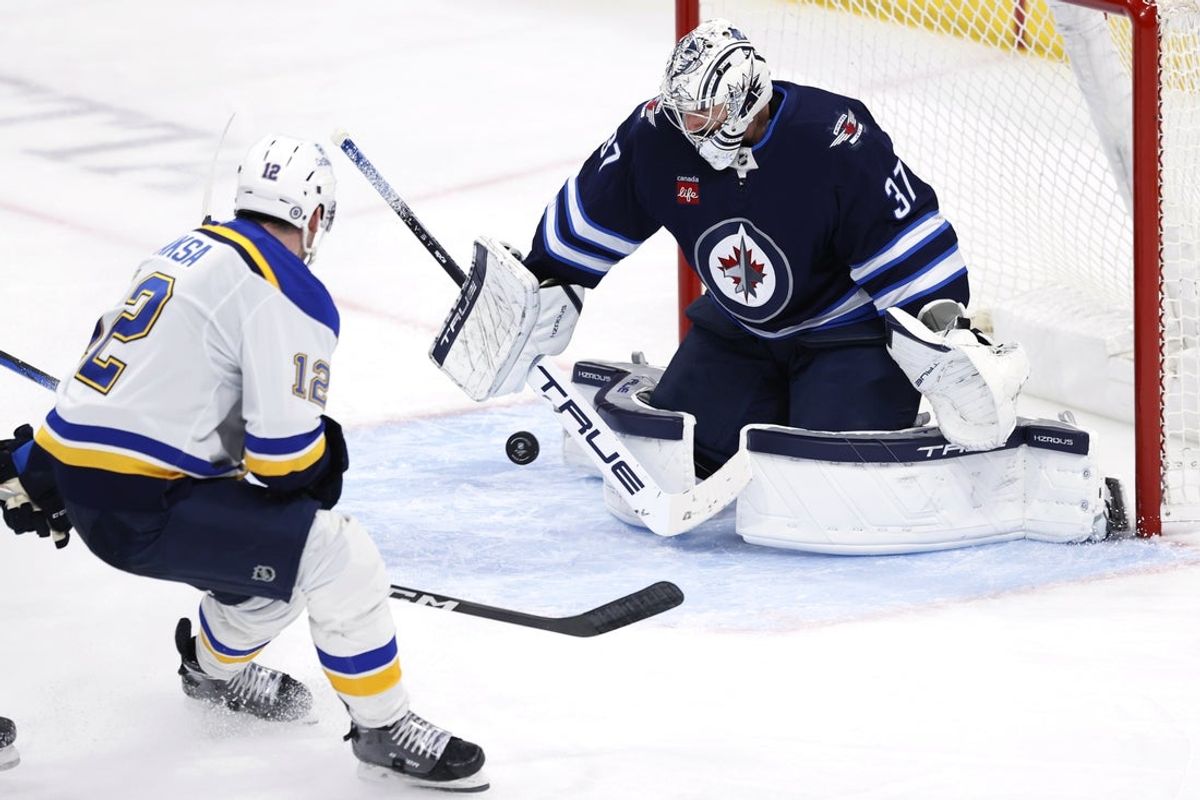 Apr 7, 2025; Winnipeg, Manitoba, CAN; Winnipeg Jets goaltender Connor Hellebuyck (37) blocks a shot from St. Louis Blues center Radek Faksa (12) in the third period at Canada Life Centre. Mandatory Credit: James Carey Lauder-Imagn Images