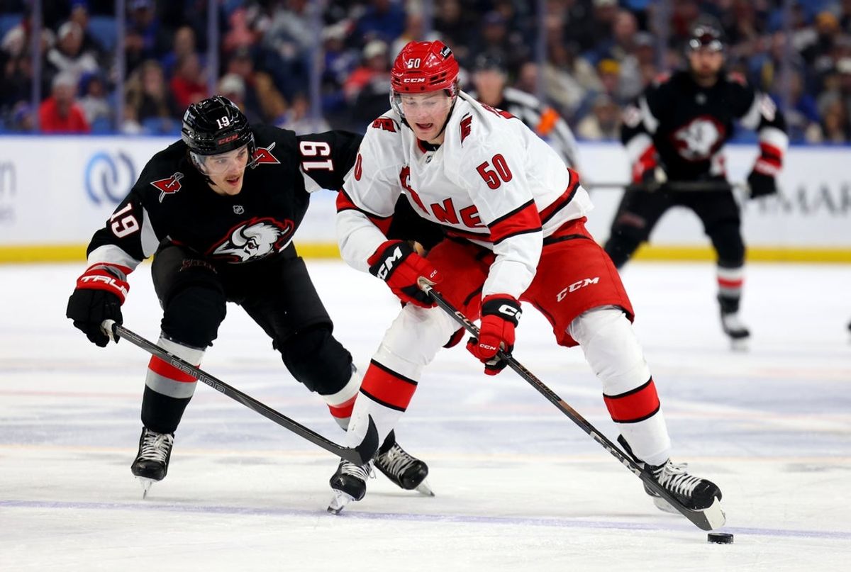 Apr 8, 2025; Buffalo, New York, USA;  Carolina Hurricanes left wing Eric Robinson (50) controls the puck as Buffalo Sabres center Peyton Krebs (19) tries to defend during the first period at KeyBank Center. Mandatory Credit: Timothy T. Ludwig-Imagn Images