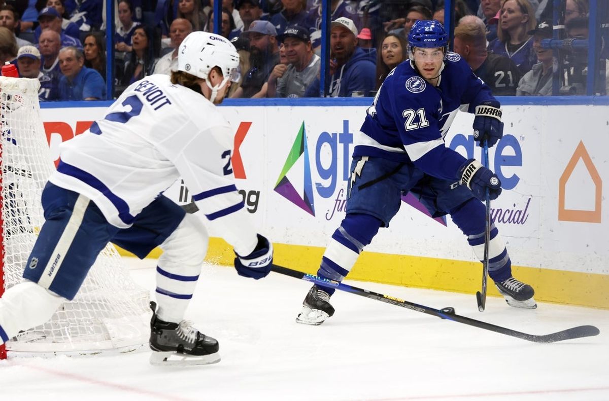 Apr 9, 2025; Tampa, Florida, USA; Tampa Bay Lightning center Brayden Point (21) passes the puck as Toronto Maple Leafs defenseman Simon Benoit (2) defends during the first period at Amalie Arena. Mandatory Credit: Kim Klement Neitzel-Imagn Images