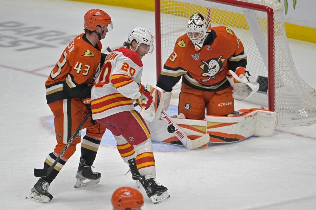 Apr 9, 2025; Anaheim, California, USA;  Anaheim Ducks defenseman Drew Helleson (43) leans on Calgary Flames left wing Blake Coleman (20) as Anaheim Ducks goaltender Ville Husso (33) makes a save during the second period at Honda Center. Mandatory Credit: Jayne Kamin-Oncea-Imagn Images