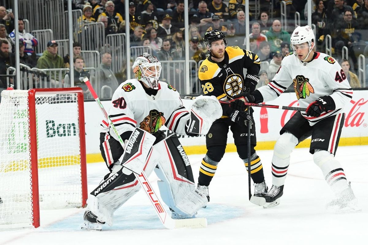 Apr 10, 2025; Boston, Massachusetts, USA;  Boston Bruins center Elias Lindholm (28) follows the play in front of Chicago Blackhawks goaltender Arvid Soderblom (40) while defenseman Louis Crevier (46) defends during the first period at TD Garden. Mandatory Credit: Bob DeChiara-Imagn Images