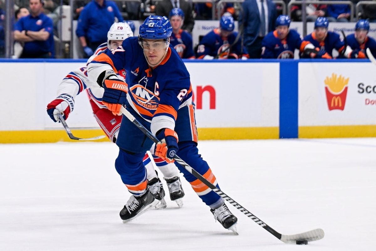 Apr 10, 2025; Elmont, New York, USA;  New York Islanders left wing Anders Lee (27) passes the puck against the New York Rangers during the second period at UBS Arena. Mandatory Credit: Dennis Schneidler-Imagn Images