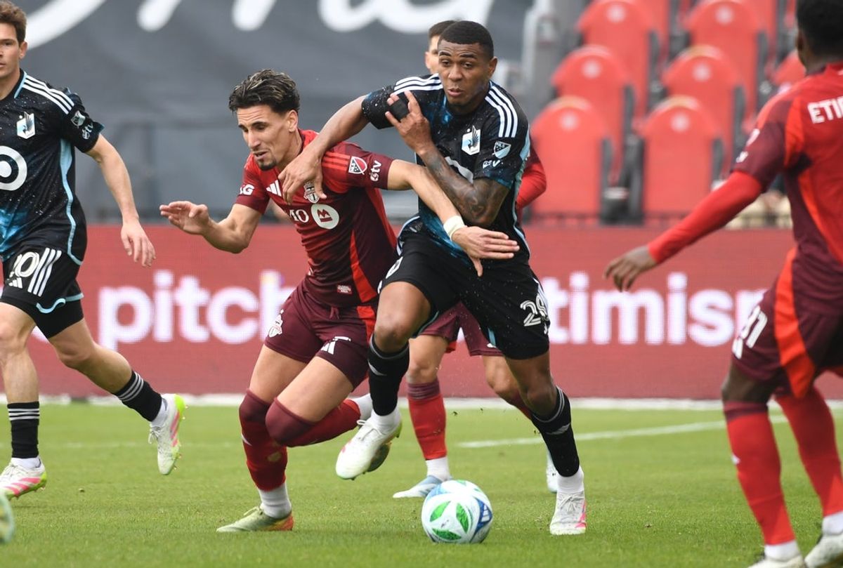 Apr 12, 2025; Toronto, Ontario, CAN;  Minnesota United defender Jefferson Diaz (28) takes the ball away from Toronto FC midfielder Theo Corbeanu (7) in the first half at BMO Field. Mandatory Credit: Dan Hamilton-Imagn Images