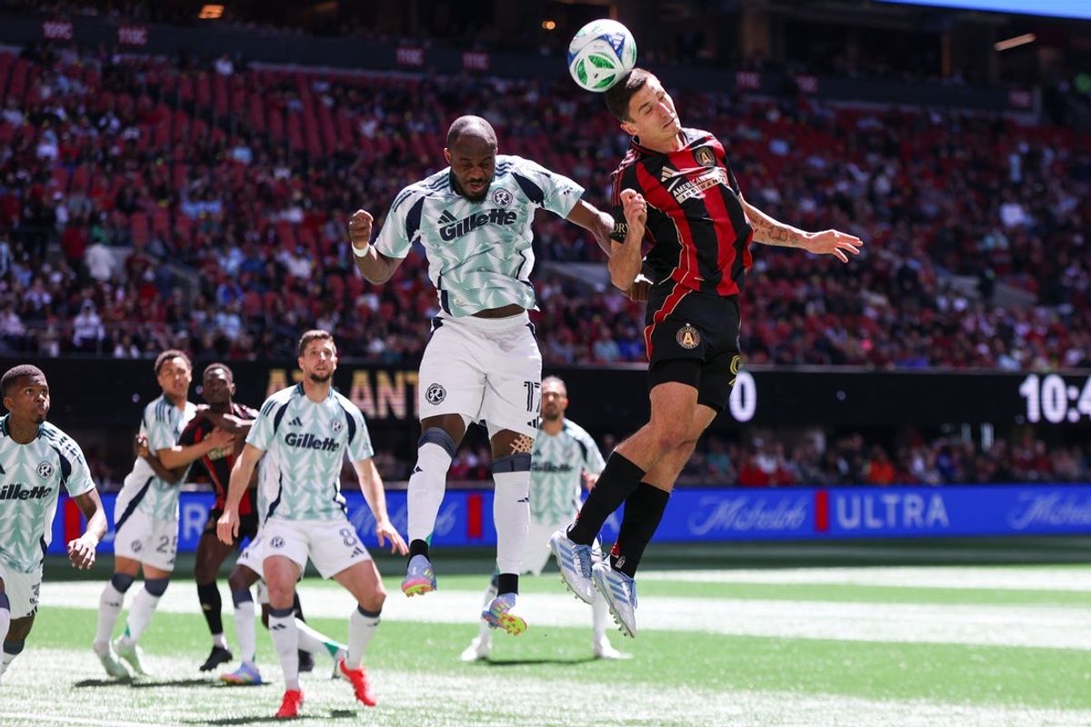 Apr 12, 2025; Atlanta, Georgia, USA; Atlanta United midfielder Bartosz Slisz (99) hits a header in front of New England Revolution forward Ignatius Ganago (17) in the first half at Mercedes-Benz Stadium. Mandatory Credit: Brett Davis-Imagn Images