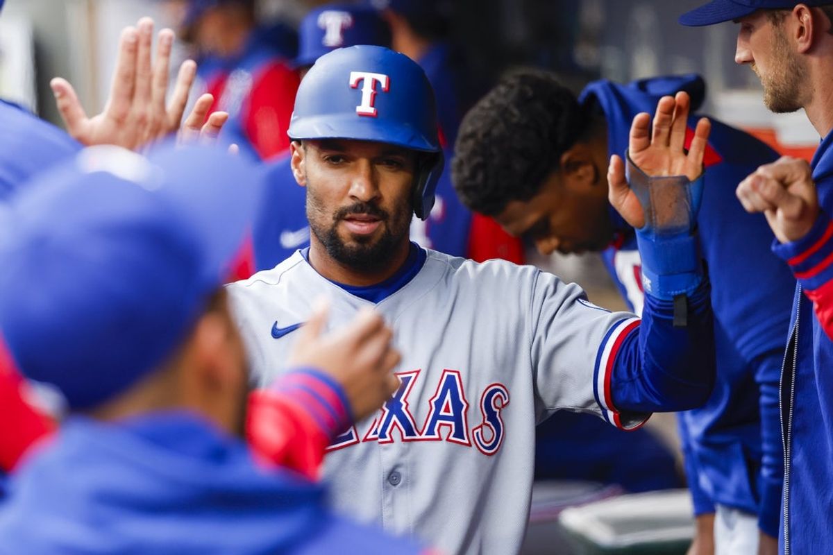 Apr 12, 2025; Seattle, Washington, USA; Texas Rangers second baseman Marcus Semien (2) high-fives teammates in the dugout after scoring a run against the Seattle Mariners during the first inning at T-Mobile Park. Mandatory Credit: Joe Nicholson-Imagn Images