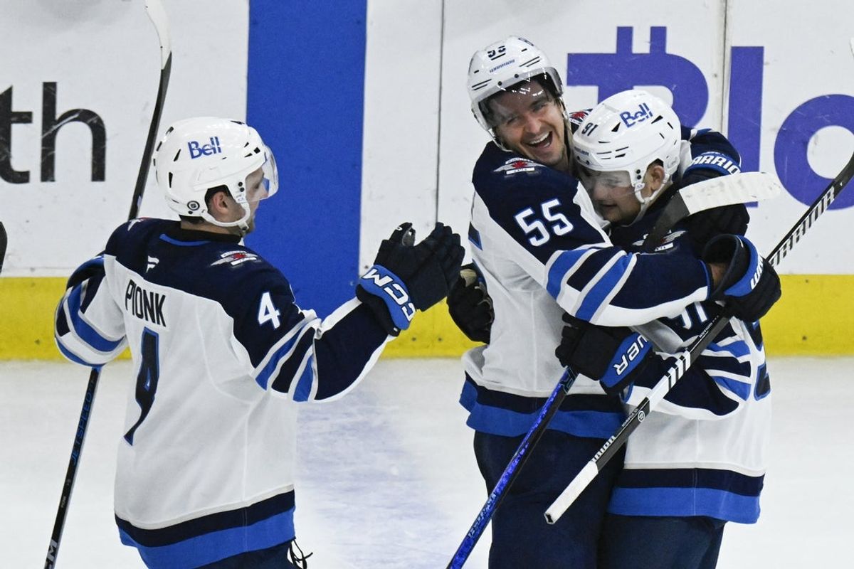 Apr 12, 2025; Chicago, Illinois, USA;  Winnipeg Jets center Cole Perfetti (91) celebrates with  center Mark Scheifele (55) and defenseman Neal Pionk (4) after he scores the game winning shootout goal against the Chicago Blackhawks during the overtime period at United Center. Mandatory Credit: Matt Marton-Imagn Images