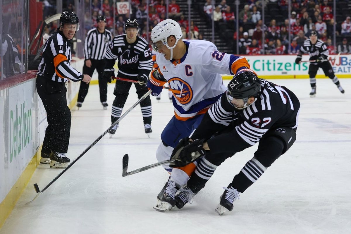 Apr 13, 2025; Newark, New Jersey, USA; New York Islanders left wing Anders Lee (27) plays the puck as New Jersey Devils defenseman Brett Pesce (22) defends during the first period at Prudential Center. Mandatory Credit: Ed Mulholland-Imagn Images