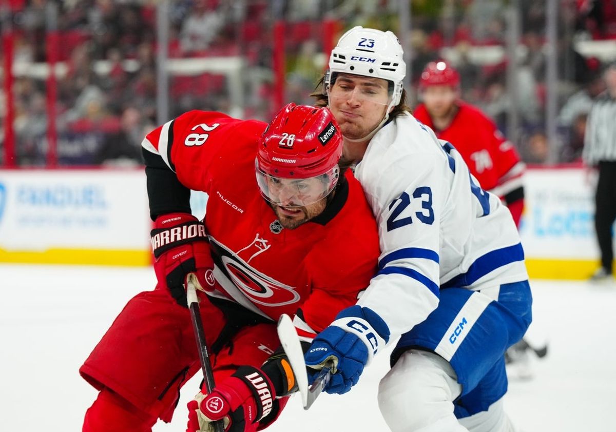 Apr 13, 2025; Raleigh, North Carolina, USA;  Carolina Hurricanes left wing William Carrier (28) and Toronto Maple Leafs left wing Matthew Knies (23) battle during the first period at Lenovo Center. Mandatory Credit: James Guillory-Imagn Images