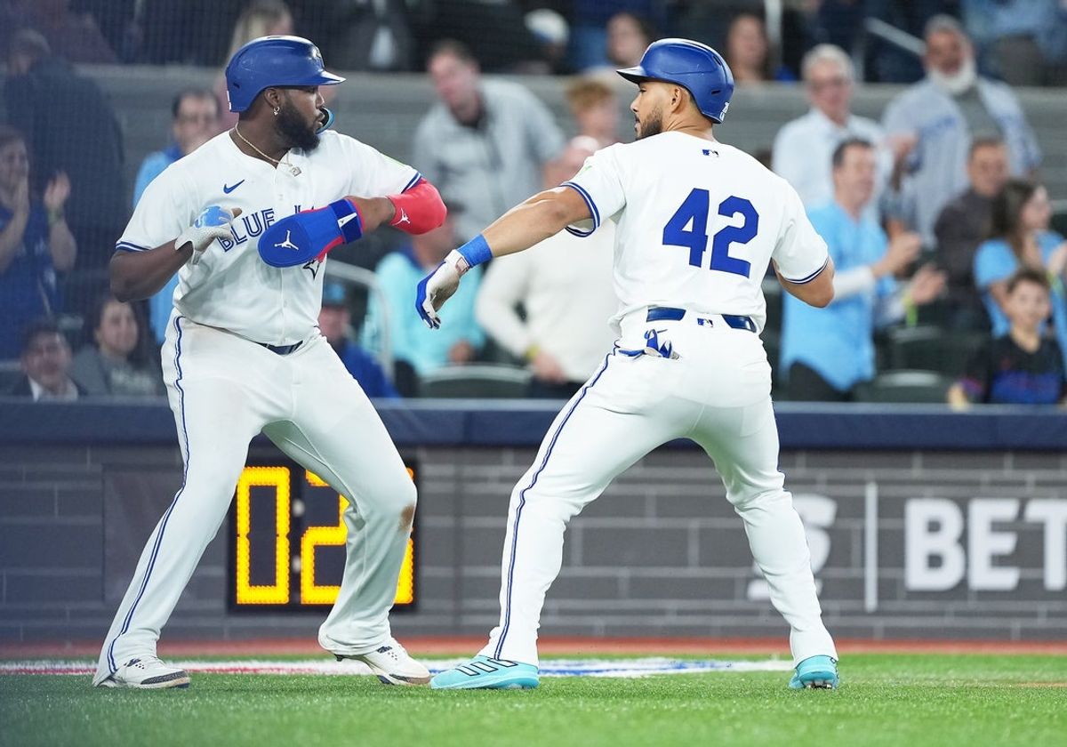 Apr 15, 2025; Toronto, Ontario, CAN; Toronto Blue Jays designated hitter Anthony Santander (25) hits a three run home run and celebrates with first baseman Vladimir Guerrero Jr. (27) against the Atlanta Braves during the fifth inning at Rogers Centre. All players wore #42 for Jackie Robinson Day. Mandatory Credit: Nick Turchiaro-Imagn Images