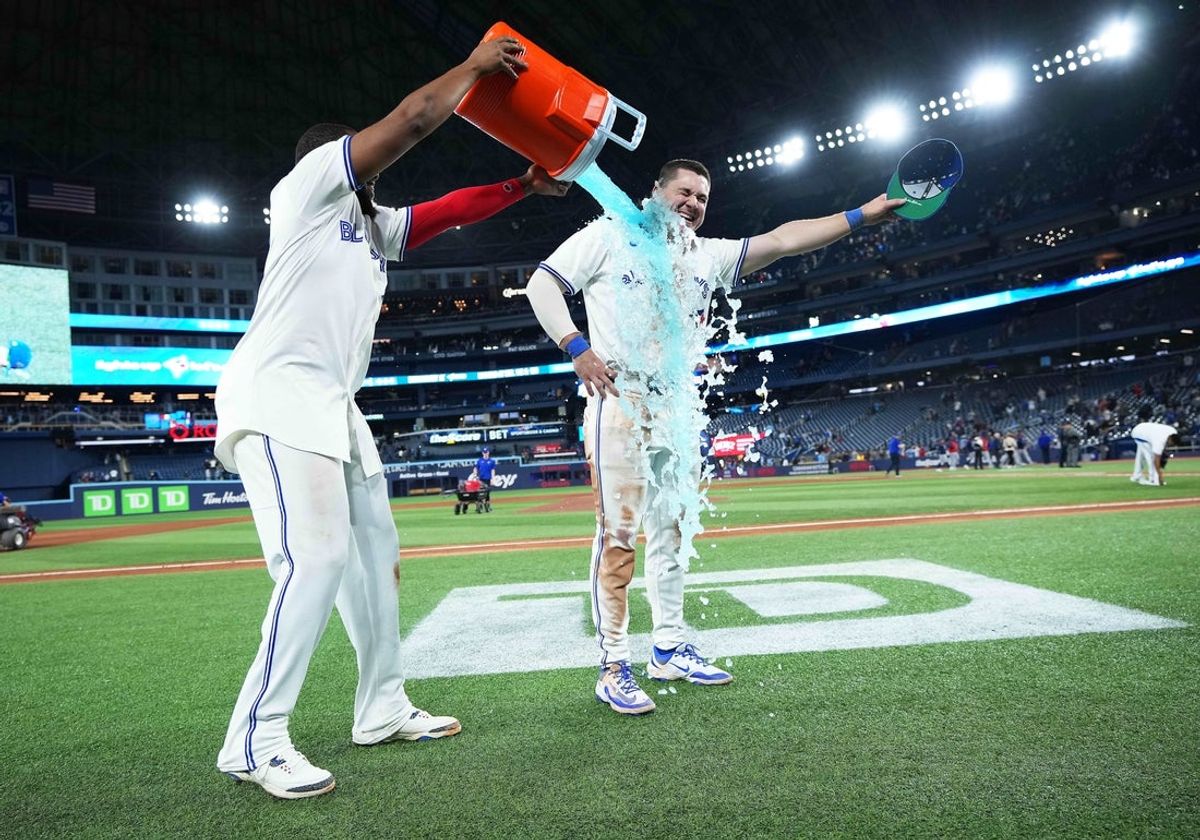 Apr 15, 2025; Toronto, Ontario, CAN; Toronto Blue Jays first base Vladimir Guerrero Jr. (27) pours the ice bucket on left fielder Alan Roden (18) against the Atlanta Braves at the end of the ninth inning at Rogers Centre. All players wore #42 for Jackie Robinson Day. Mandatory Credit: Nick Turchiaro-Imagn Images