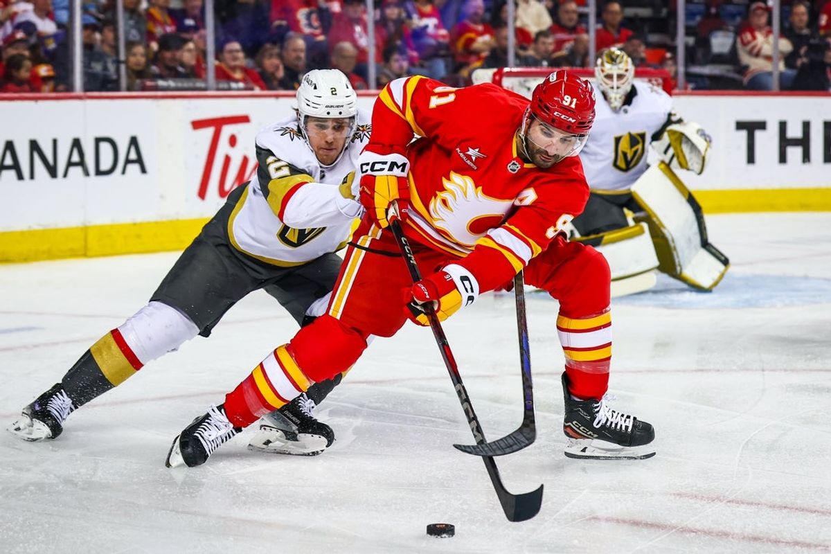Apr 15, 2025; Calgary, Alberta, CAN; Calgary Flames center Nazem Kadri (91) and Vegas Golden Knights defenseman Zach Whitecloud (2) battles for the puck during the second period at Scotiabank Saddledome. Mandatory Credit: Sergei Belski-Imagn Images
