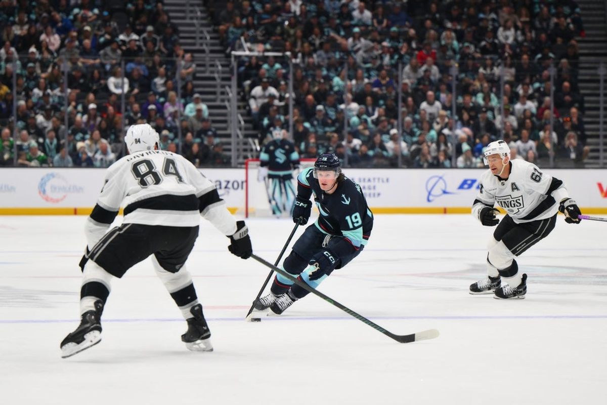 Apr 15, 2025; Seattle, Washington, USA; Seattle Kraken left wing Jared McCann (19) advances the puck while defended by Los Angeles Kings defenseman Vladislav Gavrikov (84) during the first period at Climate Pledge Arena. Mandatory Credit: Steven Bisig-Imagn Images