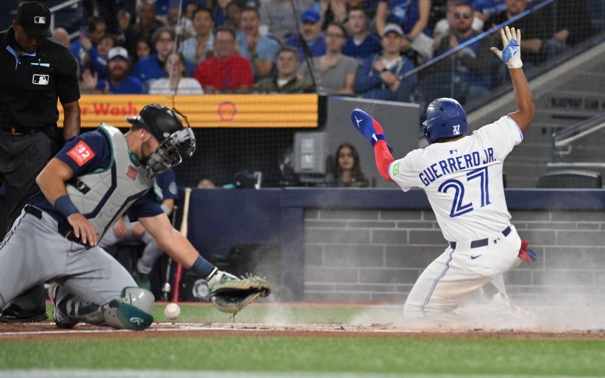 Apr 19, 2025; Toronto, Ontario, CAN;  Toronto Blue Jays first baseman Vladimir Guerrero Jr. (27) slides home to score a run as Seattle Mariners catcher Cal Raleigh (20) looks for the ball in the first inning at Rogers Centre. Mandatory Credit: Dan Hamilton-Imagn Images