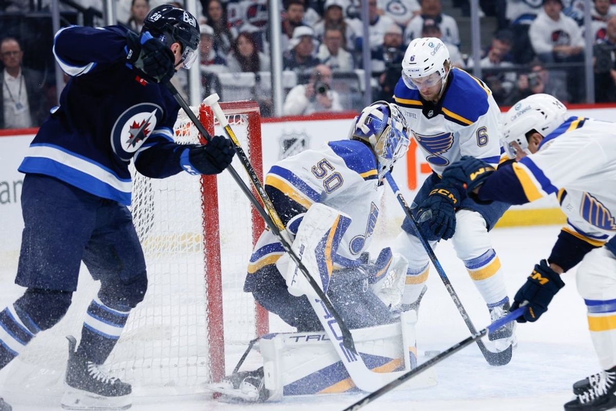 Apr 19, 2025; Winnipeg, Manitoba, CAN; St. Louis Blues defenseman Philip Broberg (6) and Winnipeg Jets forward Jaret Anderson-Dolan (28) look for the puck in front of St. Louis Blues goalie Jordan Binnington (50) during the second period in game one of the first round of the 2025 Stanley Cup Playoffs at Canada Life Centre. Mandatory Credit: Terrence Lee-Imagn Images