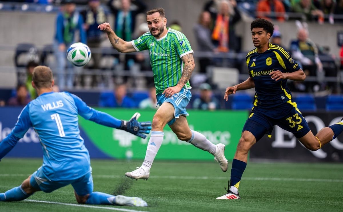 Apr 19, 2025; Seattle, Washington, USA;  Seattle Sounders forward Jordan Morris (13) takes a shot against Nashville SC goalkeeper Joe Willis (1) and defender Chris Applewhite (33) during the second half at Lumen Field. Mandatory Credit: Stephen Brashear-Imagn Images