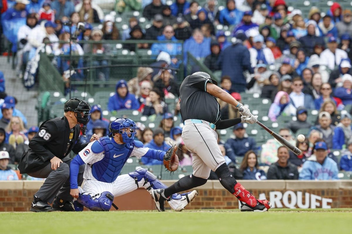 Apr 20, 2025; Chicago, Illinois, USA; Arizona Diamondbacks designated hitter Josh Naylor (22) hits an RBI-single against the Chicago Cubs during the fourth inning at Wrigley Field. Mandatory Credit: Kamil Krzaczynski-Imagn Images