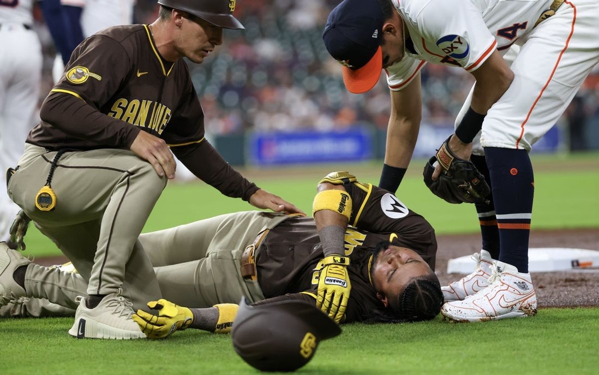 Apr 20, 2025; Houston, Texas, USA;San Diego Padres first base coach David Macias (46) and Houston Astros second baseman Mauricio Dubon (14) check on San Diego Padres designated hitter Luis Arraez (4) as he  lies on the field after colliding with Houston Astros first baseman Christian Walker (8) (not pictured )on the first base line  in the first inning  at Daikin Park. Mandatory Credit: Thomas Shea-Imagn Images