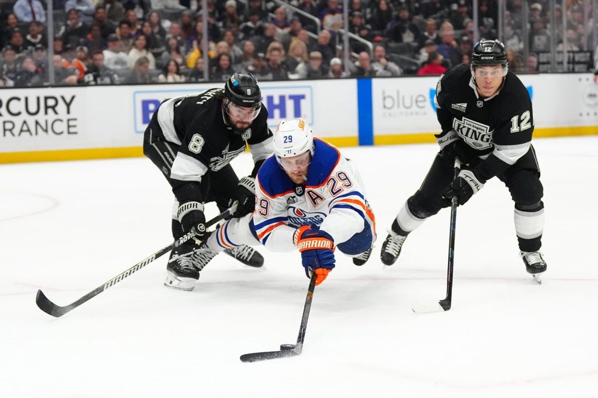 Apr 21, 2025; Los Angeles, California, USA; Edmonton Oilers center Leon Draisaitl (29) reaches for the puck against LA Kings defenseman Drew Doughty (8) and left wing Trevor Moore (12) in the third period of game one of the first round of the 2025 Stanley Cup Playoffs at Crypto.com Arena. Mandatory Credit: Kirby Lee-Imagn Images