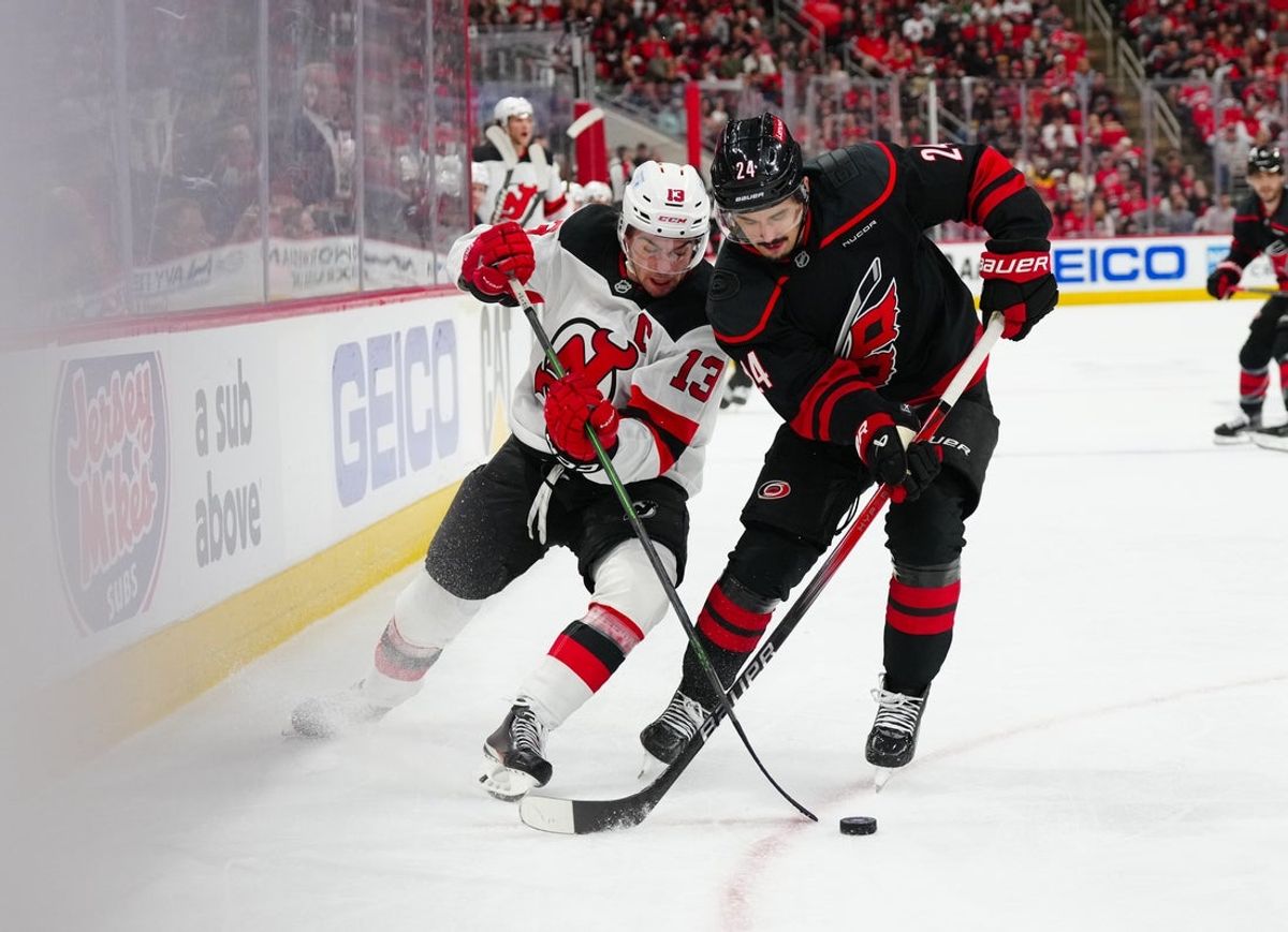 Apr 22, 2025; Raleigh, North Carolina, USA; Carolina Hurricanes center Seth Jarvis (24) and New Jersey Devils center Nico Hischier (13) battle over the puck during the first period in game two of the first round of the 2025 Stanley Cup Playoffs at Lenovo Center. Mandatory Credit: James Guillory-Imagn Images