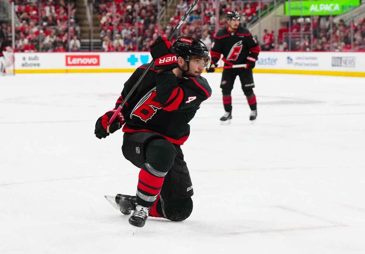 Apr 22, 2025; Raleigh, North Carolina, USA; Carolina Hurricanes defenseman Shayne Gostisbehere (4) takes a shot against the New Jersey Devils during the third period in game two of the first round of the 2025 Stanley Cup Playoffs at Lenovo Center. Mandatory Credit: James Guillory-Imagn Images