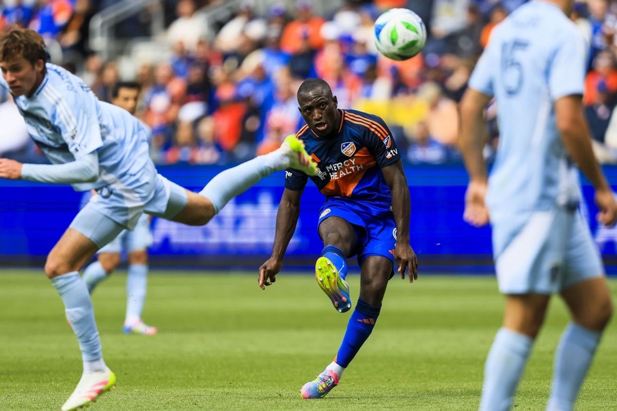 Apr 26, 2025; Cincinnati, Ohio, USA; FC Cincinnati forward Kevin Denkey (9) kicks the ball against Sporting Kansas City midfielder Jacob Bartlett (16) in the second half at TQL Stadium. Mandatory Credit: Katie Stratman-Imagn Images