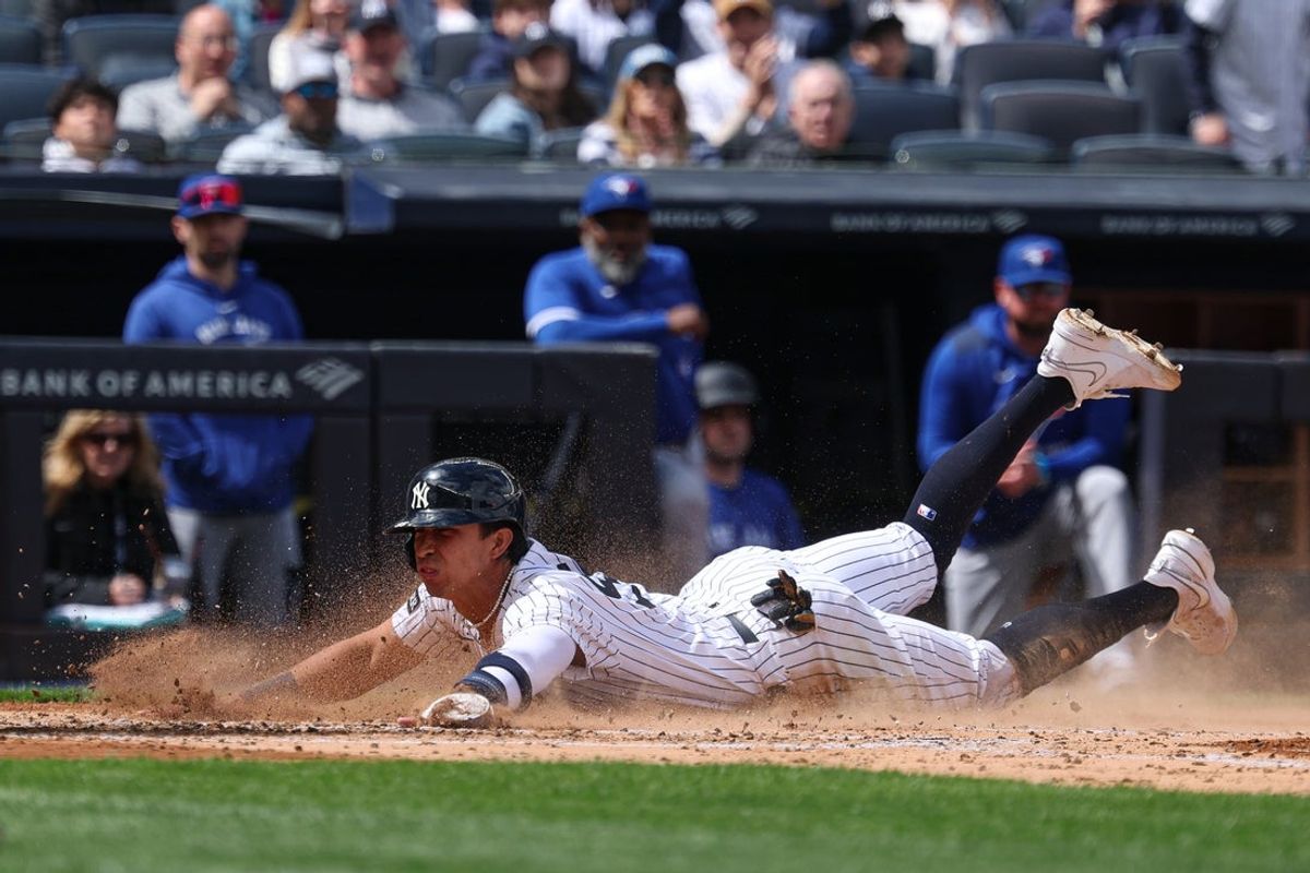 Apr 27, 2025; Bronx, New York, USA; New York Yankees third baseman Oswaldo Cabrera (95) slides in to home plate to scores a run on a sacrifice fly by center fielder Cody Bellinger (not pictured) during the third inning against the Toronto Blue Jays at Yankee Stadium. Mandatory Credit: Vincent Carchietta-Imagn Images