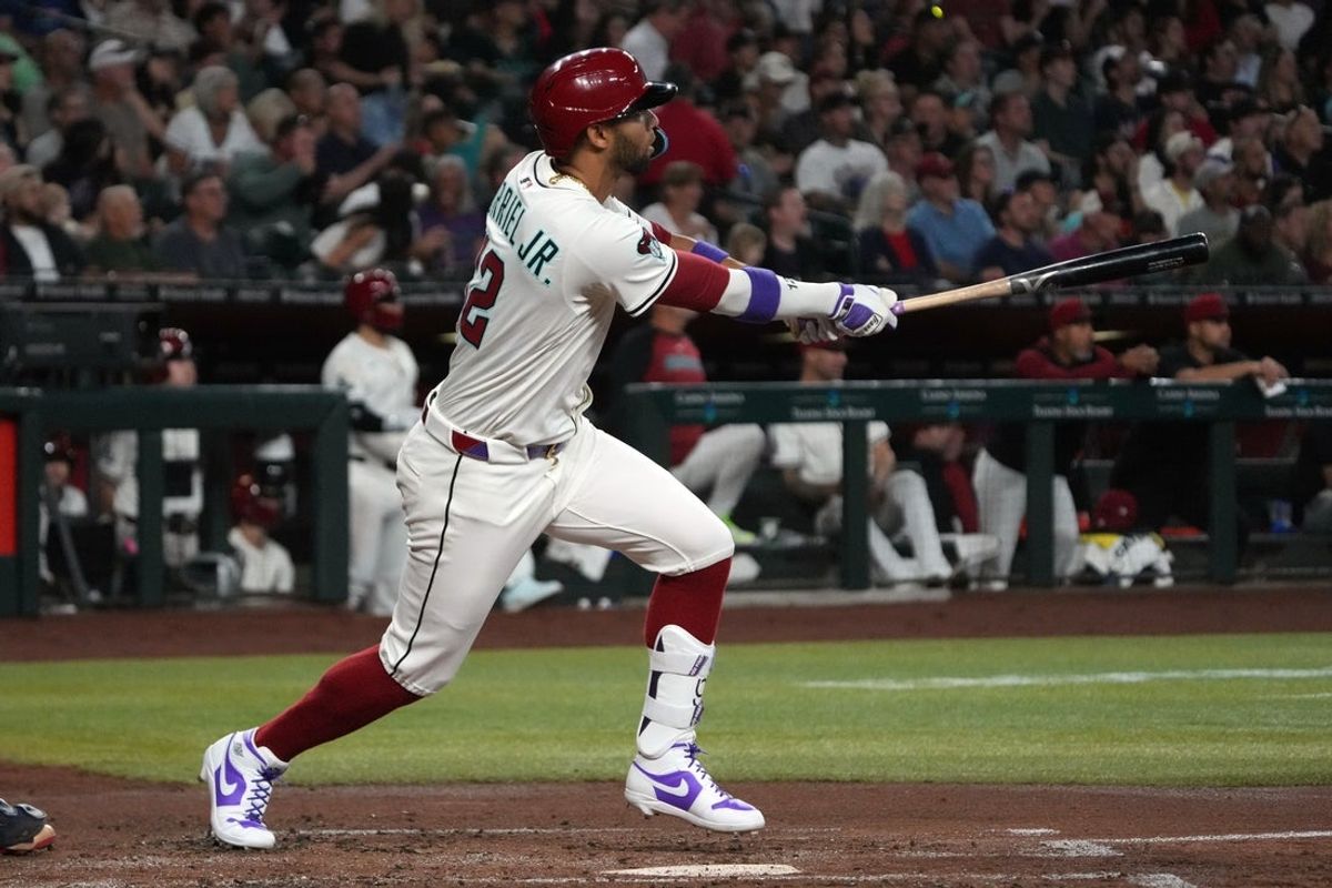 Apr 27, 2025; Phoenix, Arizona, USA; Arizona Diamondbacks outfielder Lourdes Gurriel Jr. (12) hits an RBI sacrifice fly out against the Atlanta Braves in the second inning at Chase Field. Mandatory Credit: Rick Scuteri-Imagn Images