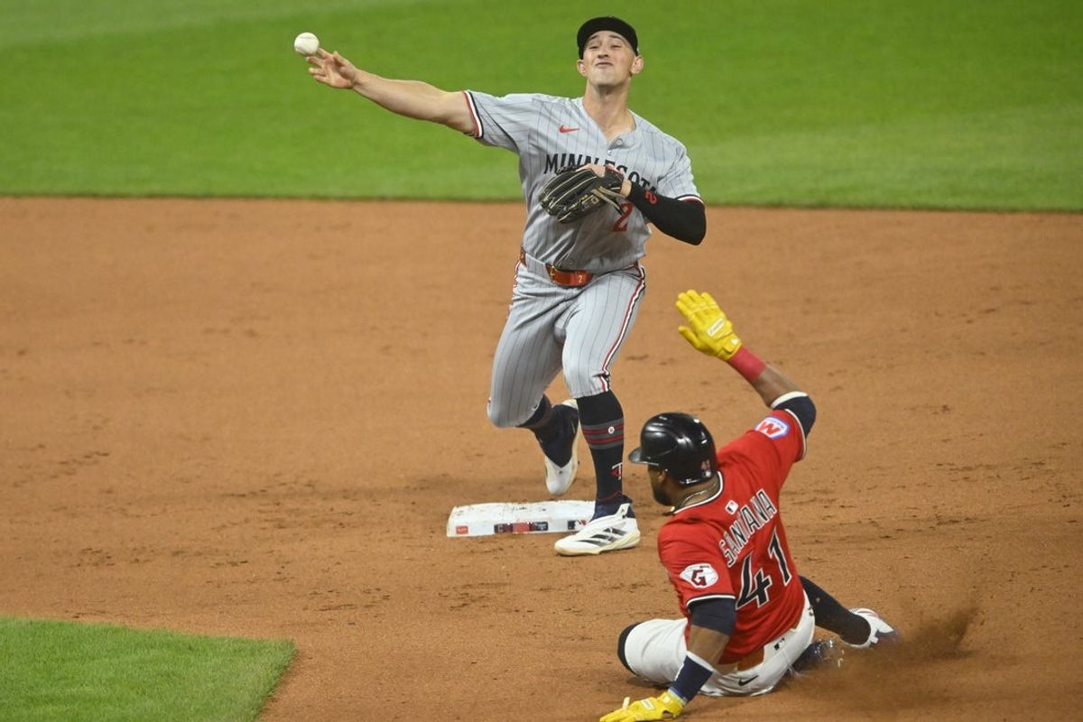 Apr 29, 2025; Cleveland, Ohio, USA; Minnesota Twins second baseman Brooks Lee (2) turns a double play beside Cleveland Guardians first baseman Carlos Santana (41) in the fourth inning at Progressive Field. Mandatory Credit: David Richard-Imagn Images