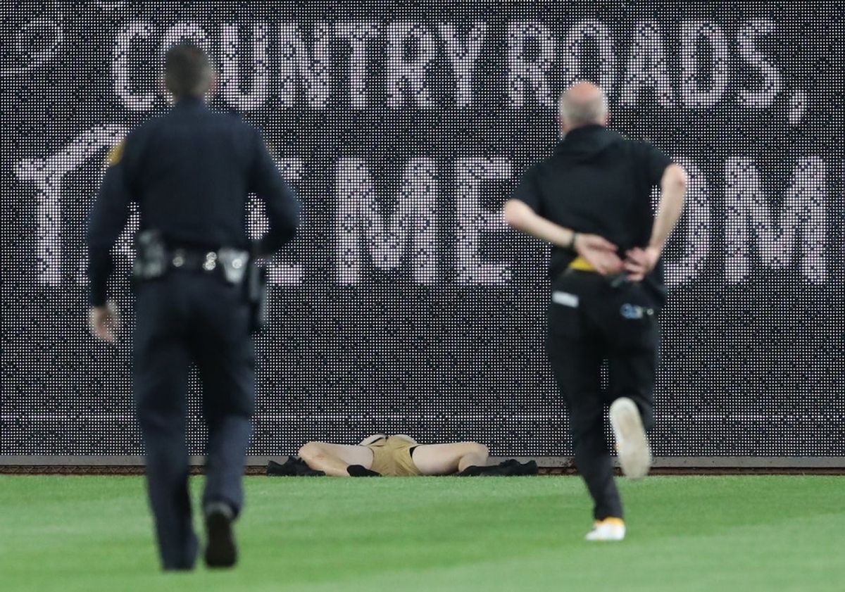 Apr 30, 2025; Pittsburgh, Pennsylvania, USA;  Stadium security and Pittsburgh Pirates medical personnel rush to assist a fan who fell from the stands to the field as the Pirates batted against the Chicago Cubs during the seventh inningat PNC Park. Mandatory Credit: Charles LeClaire-Imagn Images