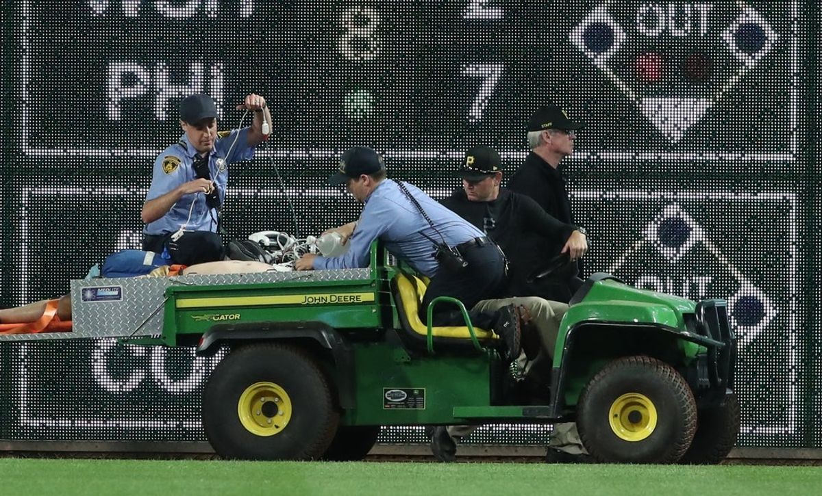 Apr 30, 2025; Pittsburgh, Pennsylvania, USA;  Stadium security and Pittsburgh Pirates medical personnel cart a fan who fell from the stands to the field to an ambulance as the Pirates batted against the Chicago Cubs during the seventh inningat PNC Park. Mandatory Credit: Charles LeClaire-Imagn Images