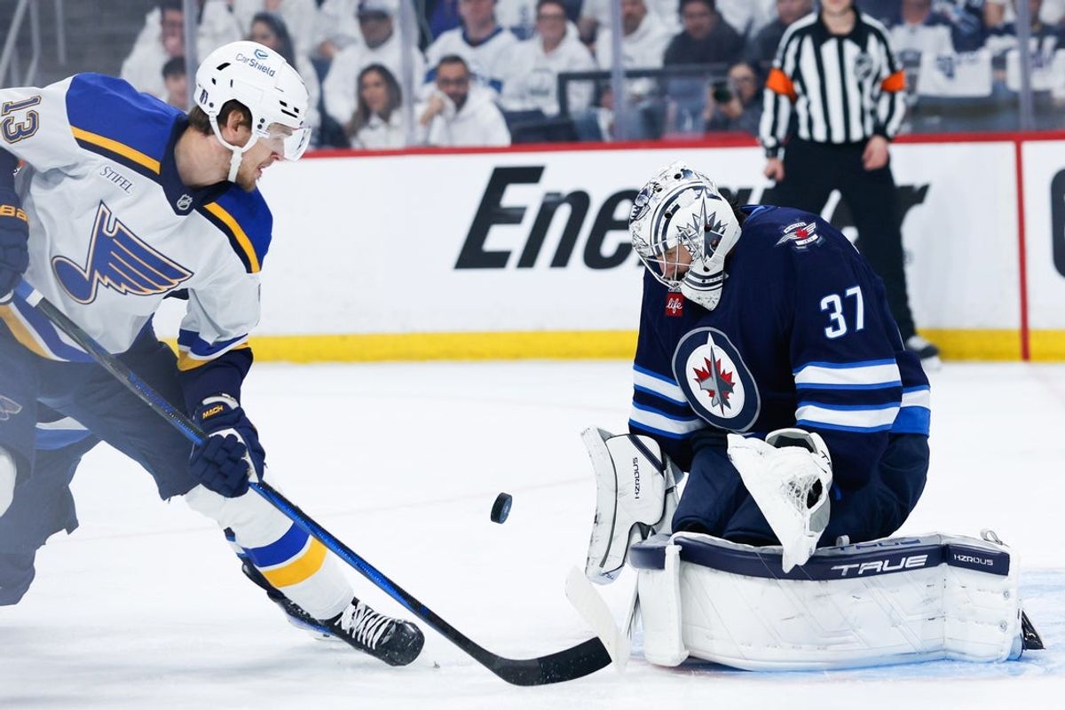 Apr 30, 2025; Winnipeg, Manitoba, CAN; Winnipeg Jets goalie Connor Hellebuyck (37) makes a save as St. Louis Blues forward Alexey Toropchenko (13) looks for a rebound during the first period in game five of the first round of the 2025 Stanley Cup Playoffs at Canada Life Centre. Mandatory Credit: Terrence Lee-Imagn Images