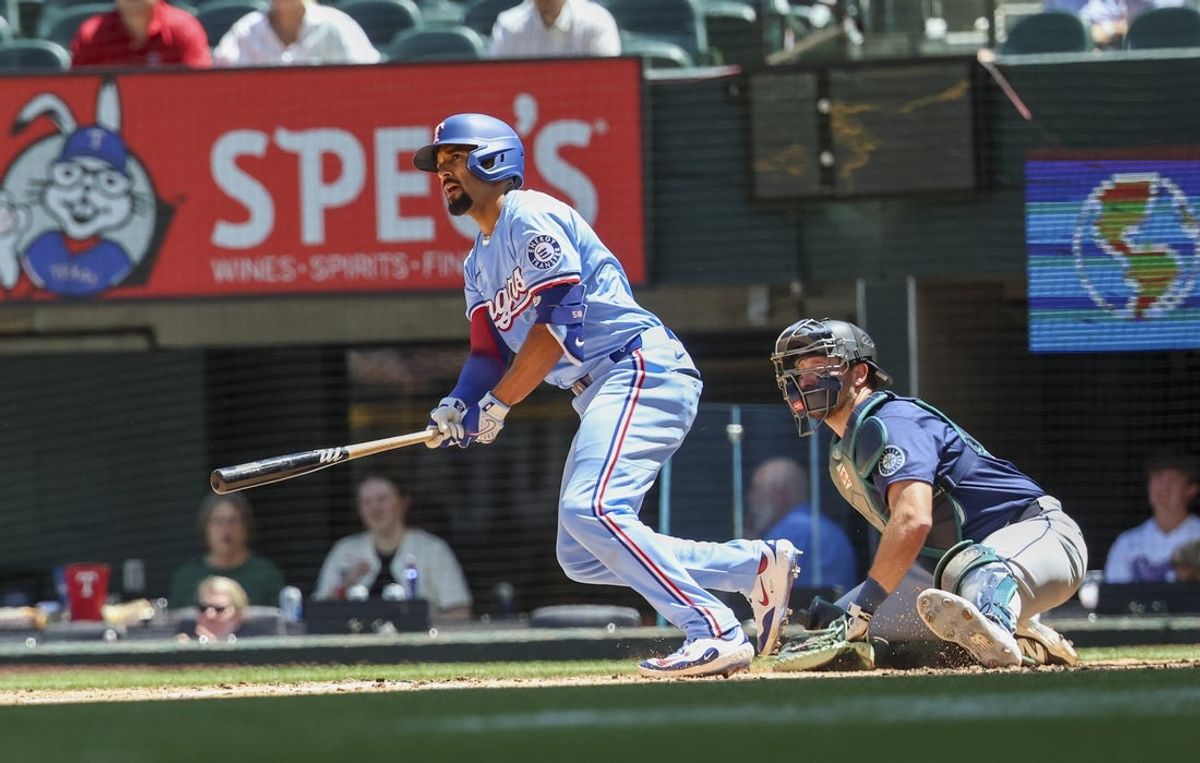 May 4, 2025; Arlington, Texas, USA;  Texas Rangers shortstop Corey Seager (5) hits an rbi single during the third inning against the Seattle Mariners at Globe Life Field. Mandatory Credit: Kevin Jairaj-Imagn Images
