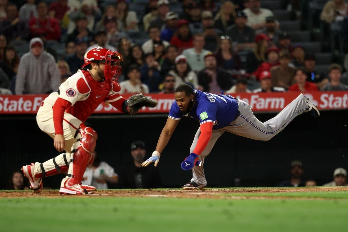 May 7, 2025; Anaheim, California, USA;  Toronto Blue Jays first baseman Vladimir Guerrero Jr. (27) scores on a single by designated hitter Anthony Santander (25, not pictured) as Los Angeles Angels catcher Travis d'Arnaud (25) waits for the ball during the sixth inning at Angel Stadium. Mandatory Credit: Kiyoshi Mio-Imagn Images