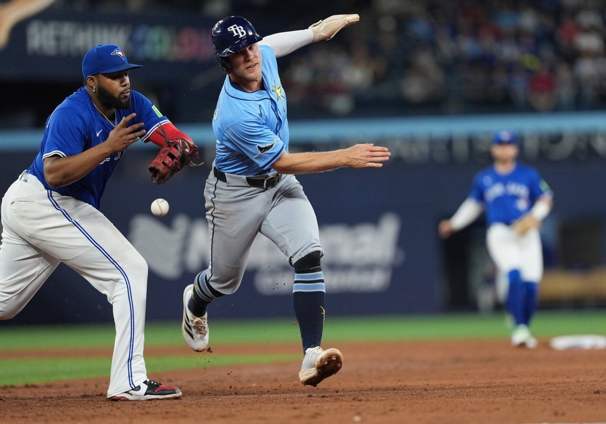 May 13, 2025; Toronto, Ontario, CAN; Toronto Blue Jays first baseman Vladimir Guerrero Jr. (27) has the ball come out of his glove as he tries to tag Tampa Bay Rays shortstop Taylor Walls (6) in a run down scoring a run during the sixth inning at Rogers Centre. Mandatory Credit: Nick Turchiaro-Imagn Images