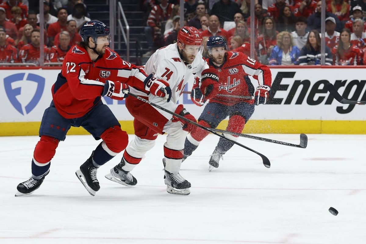 May 15, 2025; Washington, District of Columbia, USA; Washington Capitals right wing Brandon Duhaime (22) and Carolina Hurricanes defenseman Jaccob Slavin (74) chase the puck in the first period in game five of the second round of the 2025 Stanley Cup Playoffs at Capital One Arena. Mandatory Credit: Geoff Burke-Imagn Images