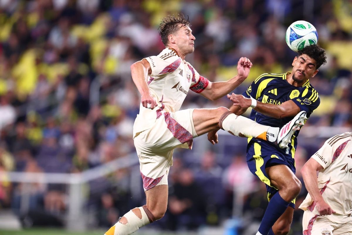 May 17, 2025; Nashville, Tennessee, USA; D.C. United defender David Schnegg (28) jumps to kick the ball and collides with Nashville SC midfielder Ahmed Qasem (37) as he heads the ball in the first half at Geodis Park. Mandatory Credit: Casey Gower-Imagn Images