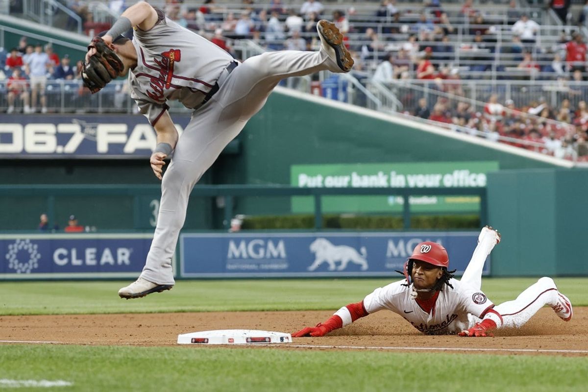 May 20, 2025; Washington, District of Columbia, USA; Washington Nationals shortstop CJ Abrams (5) slides into third base after an errant throw gets past Atlanta Braves third baseman Austin Riley (27) during the second inning at Nationals Park. Mandatory Credit: Geoff Burke-Imagn Images