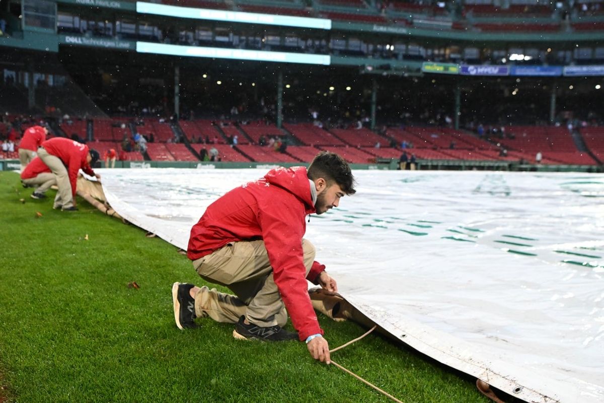 May 23, 2025; Boston, Massachusetts, USA; Grounds crew members cover the infield after a game between the Baltimore Orioles and Boston Red Sox was postponed at Fenway Park. Mandatory Credit: Brian Fluharty-Imagn Images
