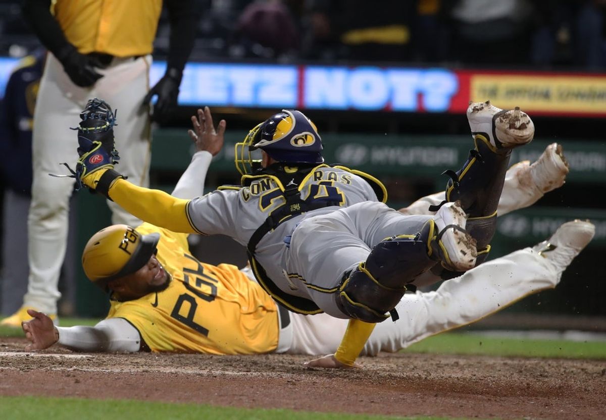 May 23, 2025; Pittsburgh, Pennsylvania, USA;  Milwaukee Brewers catcher William Contreras (24) dives in an attempt to tag Pittsburgh Pirates outfielder Alexander Canario (rear) out at home plate during the tenth inning at PNC Park. Canario was ruled out for leaving the baseline. Mandatory Credit: Charles LeClaire-Imagn Images