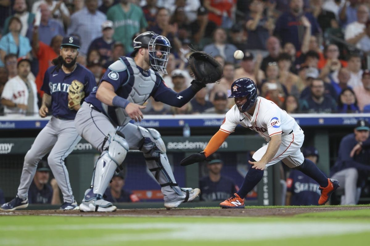 May 24, 2025; Houston, Texas, USA; Houston Astros second baseman Jose Altuve (27) slides to score a run as Seattle Mariners catcher Mitch Garver (18) fields a throw during the first inning at Daikin Park. Mandatory Credit: Troy Taormina-Imagn Images