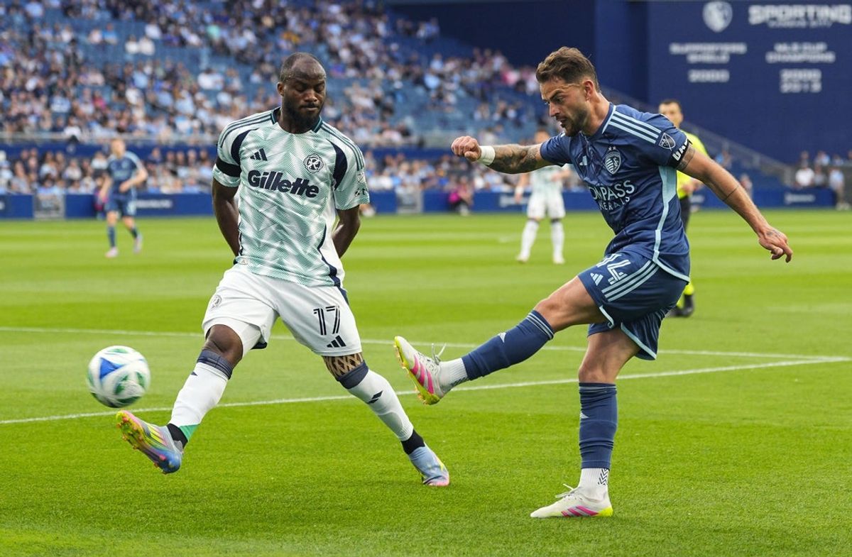 May 24, 2025; Kansas City, Kansas, USA; Sporting Kansas City defender Tim Leibold (14) crosses the ball against New England Revolution forward Ignatius Ganago (17) during the first half at Children's Mercy Park. Mandatory Credit: Jay Biggerstaff-Imagn Images