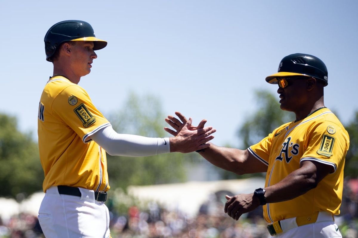 May 25, 2025; West Sacramento, California, USA; Athletics first baseman Logan Davidson (6) gets a congratulatory handshake from third base coach Eric Martins after getting his first hit and RBI against the Philadelphia Phillies during the first inning at Sutter Health Park. Mandatory Credit: D. Ross Cameron-Imagn Images