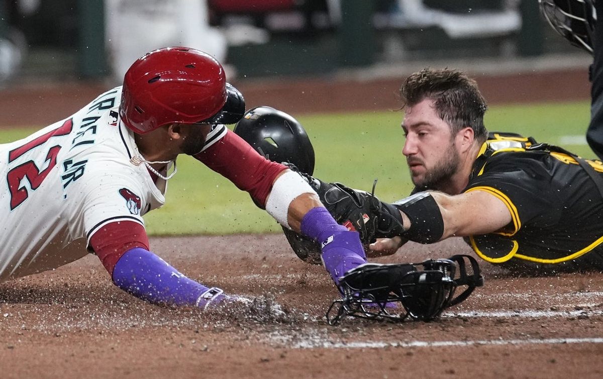 Arizona Diamondbacks base runner Lourdes Gurriel Jr. (12) is tagged out at home plate by Pittsburgh Pirates catcher Joey Bart (14) at Chase Field in Phoenix on May 27, 2025.