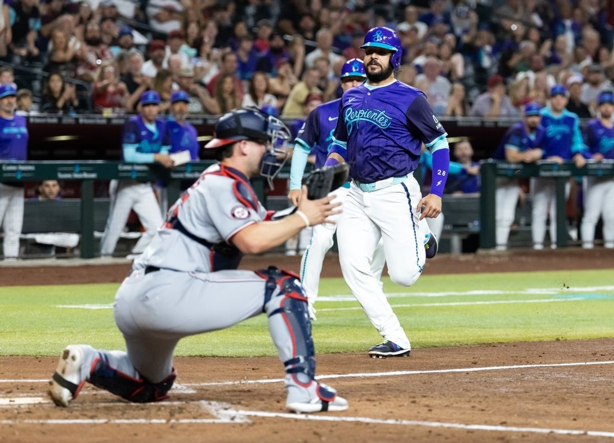 May 30, 2025; Phoenix, Arizona, USA; Arizona Diamondbacks base runner Eugenio Suarez (right) runs home prior to being tagged out by Washington Nationals catcher Riley Adams in the third inning at Chase Field. Mandatory Credit: Mark J. Rebilas-Imagn Images
