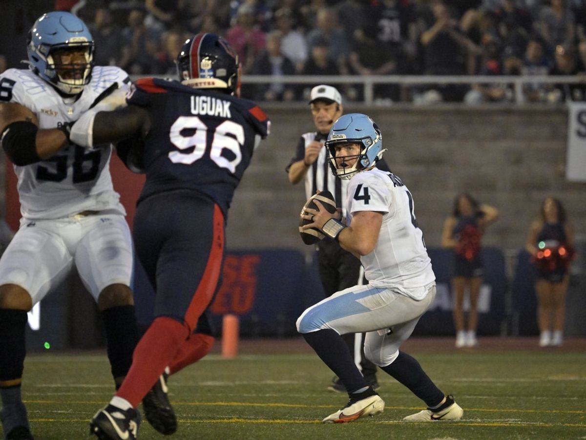 Jun 6, 2025; Montreal, Quebec, Canada; Toronto Argonauts quarterback  Nick Arbuckle (4) passes the ball as Montreal Alouettes defensive lineman Lwal Uguak (96) rushes during the first half at Percival-Molson stadium. Mandatory Credit: Eric Bolte-Imagn Images
