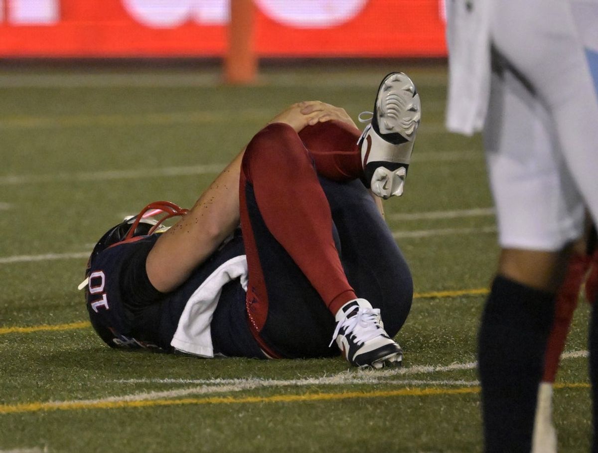 Jun 6, 2025; Montreal, Quebec, Canada; Montreal Alouettes quarterback  Davis Alexander (10) grabs his leg after a hit during the second half against the Toronto Argonauts at Percival-Molson stadium. Mandatory Credit: Eric Bolte-Imagn Images