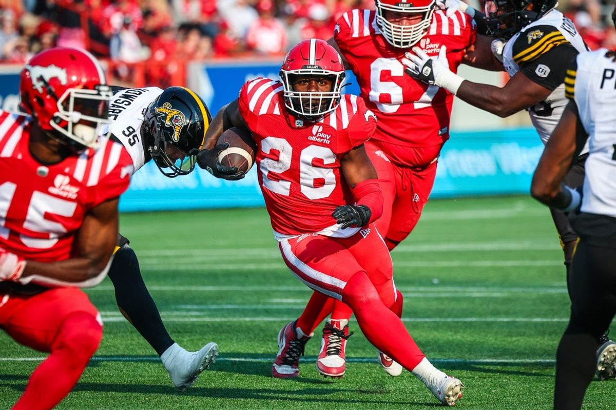 Jun 7, 2025; Calgary, Alberta, Canada; Calgary Stampeders running back Dedrick Mills (26) runs with the ball against the Hamilton Tiger-Cats during the second half at McMahon Stadium. Mandatory Credit: Sergei Belski-Imagn Images
