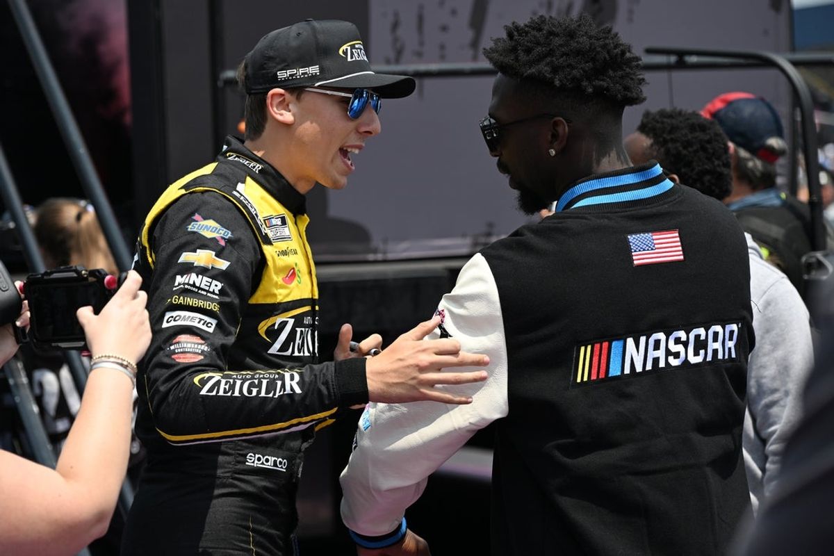 Jun 8, 2025; Brooklyn, Michigan, USA; NASCAR Cup Series driver Carson Hocevar (77) greets Detroit Lions safety Kerby Joseph during driver introductions before the start of the FireKeepers Casino 400 at Michigan International Speedway. Mandatory Credit: Lon Horwedel-Imagn Images
